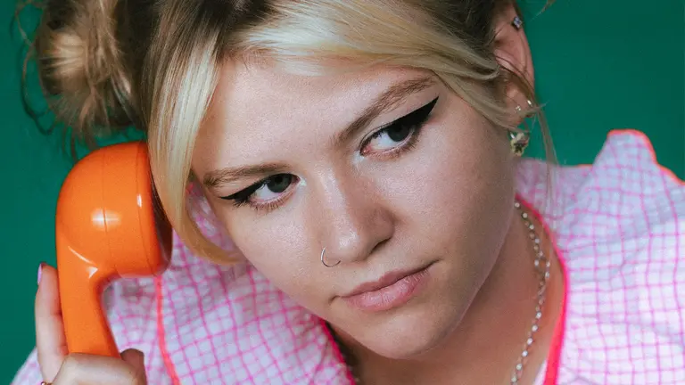 a woman holds an orange telephone to her ear