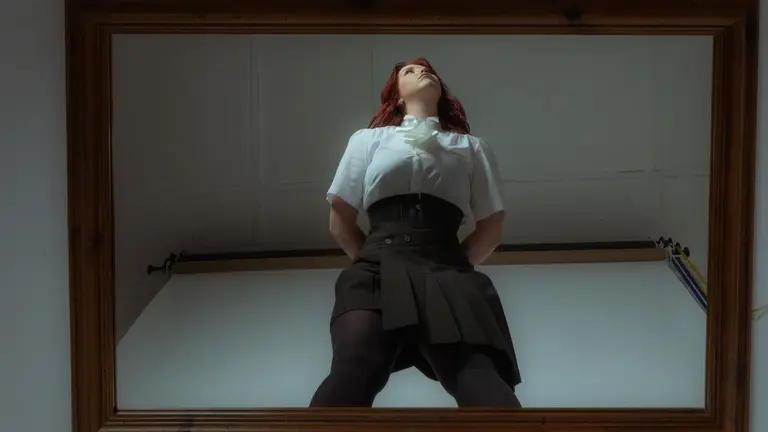 a woman with red hair is pictured from below. she wears a striking corporate style outfit