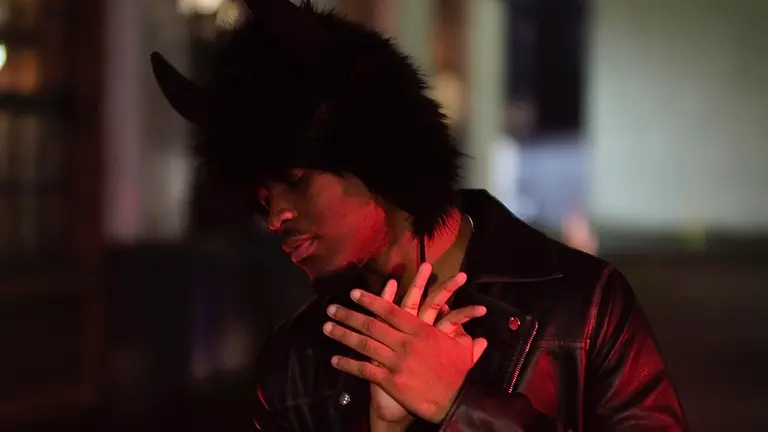 a man wearing a furry hat with horns places his hands across his chest