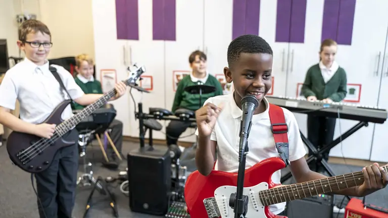 Five children playing different instruments in a Rocksteady classroom