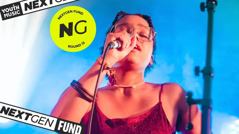 A singer passionately performs on stage, holding a microphone, bathed in vibrant blue and pink lights. "Youth Music NextGen Fund Round 12" logo displayed.