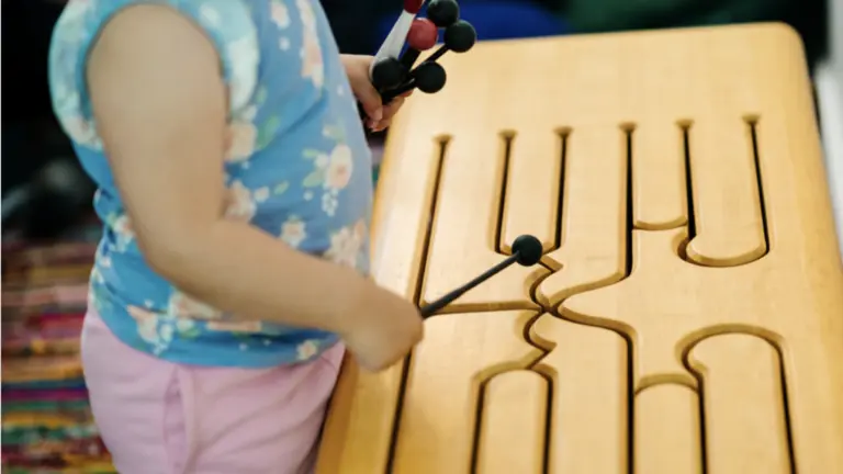 A young child playing with an electric xylophone