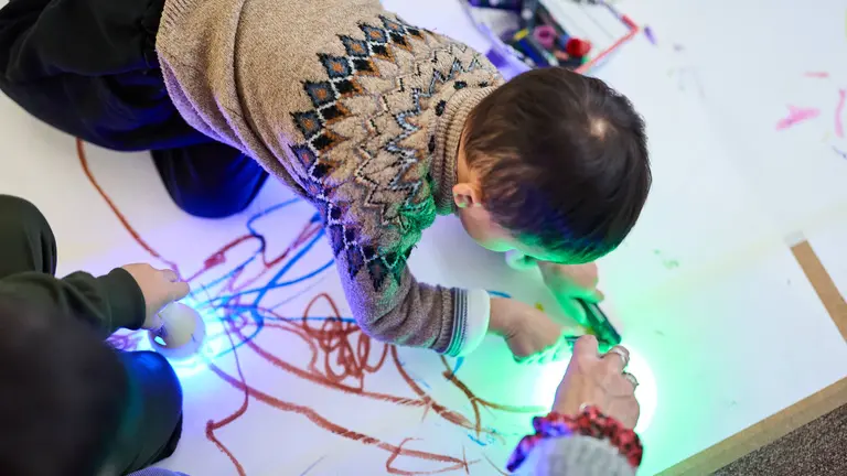 child in grey jumper drawing 