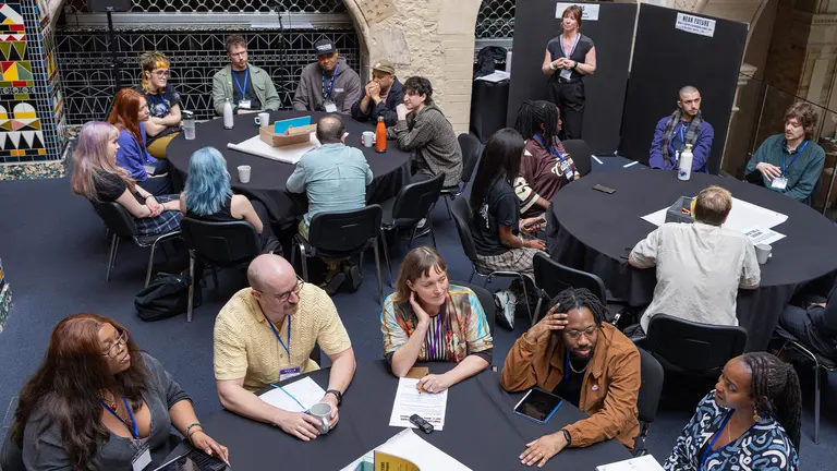 groups of people sit on round tables and talk