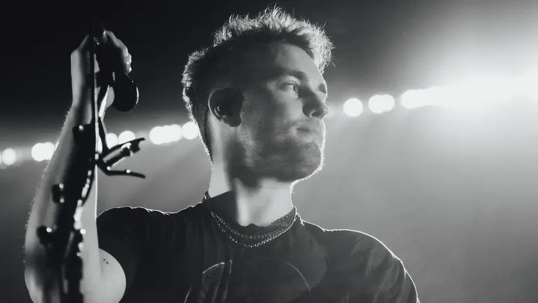 sam fender holds a microphone stand and looks to the left 