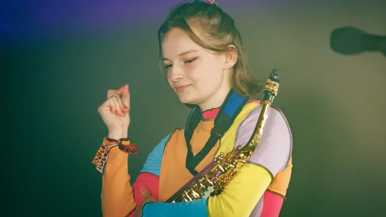 Young woman in a colourful top with a saxophone on stage