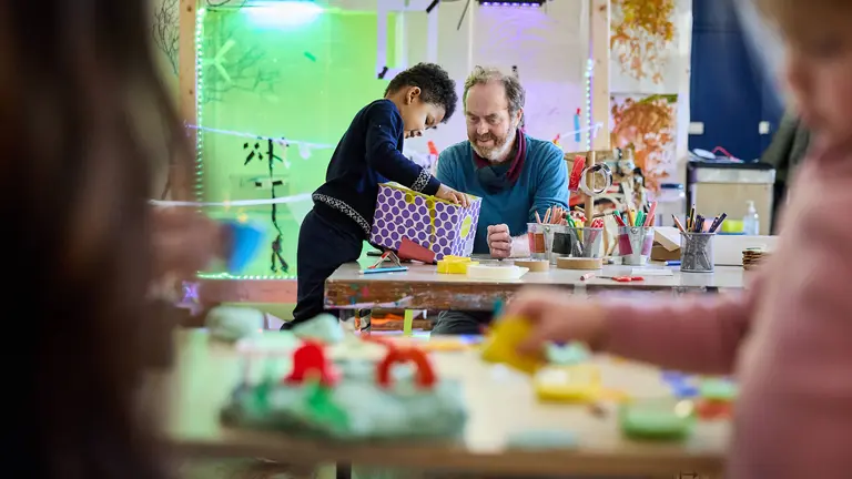an early years session where a child is playing with art and crafts tools with the practitioner