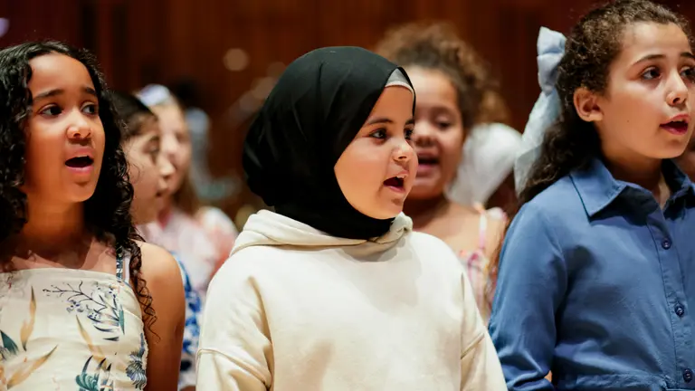 young girls standing in rows singing and looking off camera