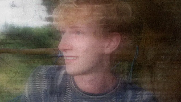 Jakey outside in green space, looking away from the camera with a blurry affect