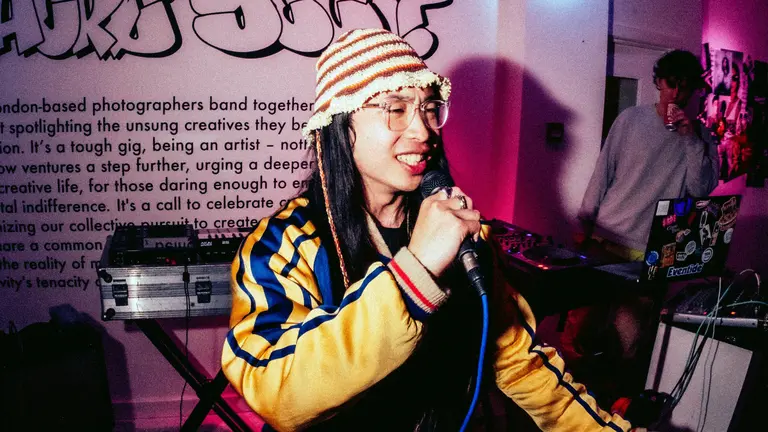 Kei Wei on stage with a tracksuit and a hat