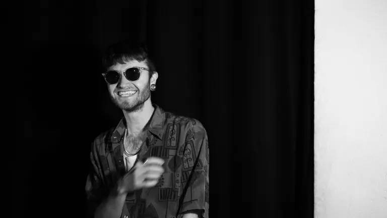 Samiel in black and white, wearing shades and laughing at the camera