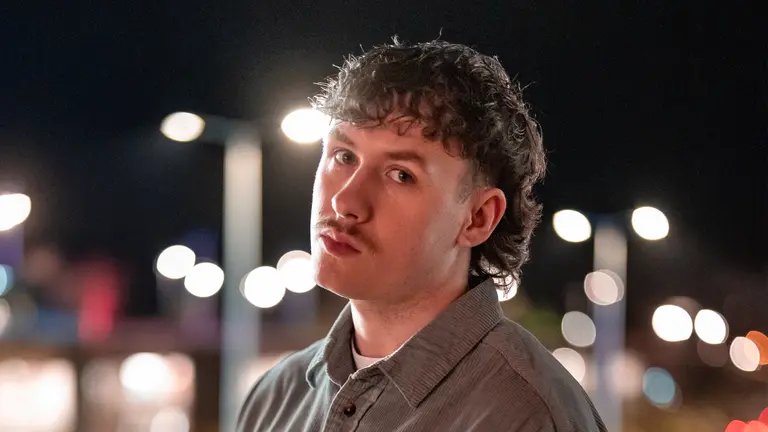 Headshot outside, looking at the camera, with street lights behind