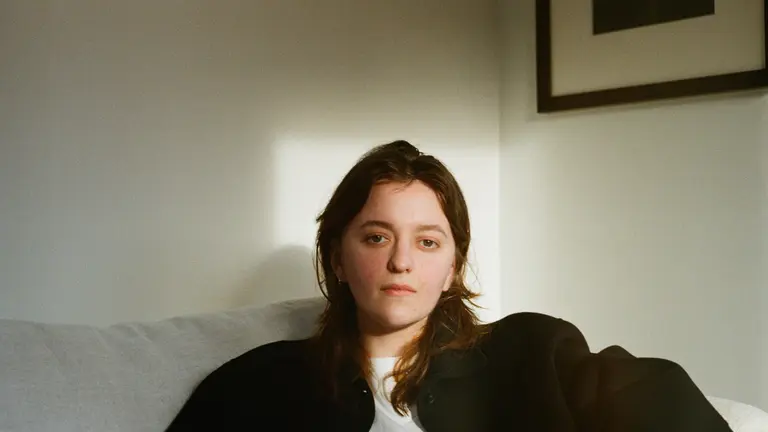 Eddie in a living room with light on their face, looking straight into the camera