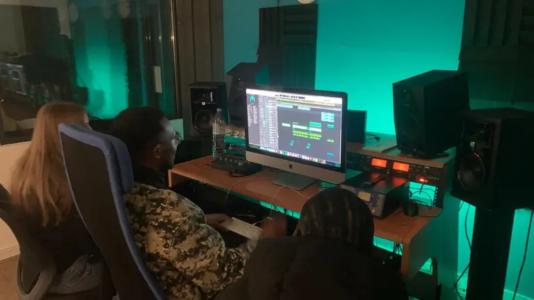 Two young people in front of a computer using a music software