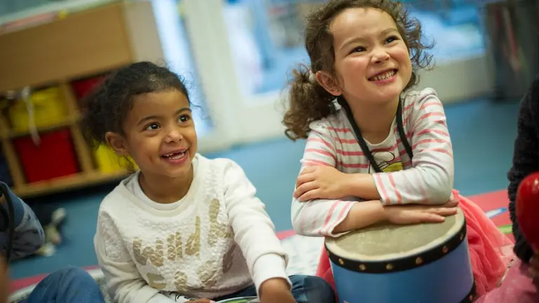 Two young children laugh at someone out of frame. One of them have a 