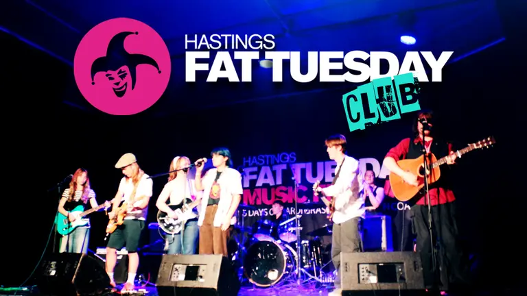 Six people in a scenario playing instruments. There's a banner on top that says "Hastings Fat Tuesday Club"