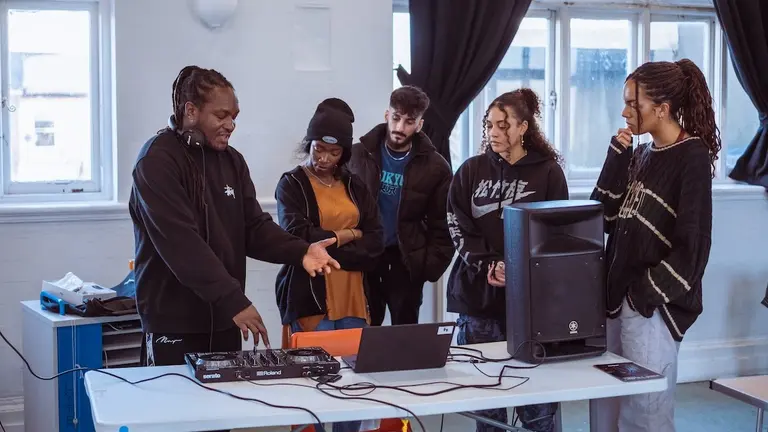 A person shows four young people musical equipment 