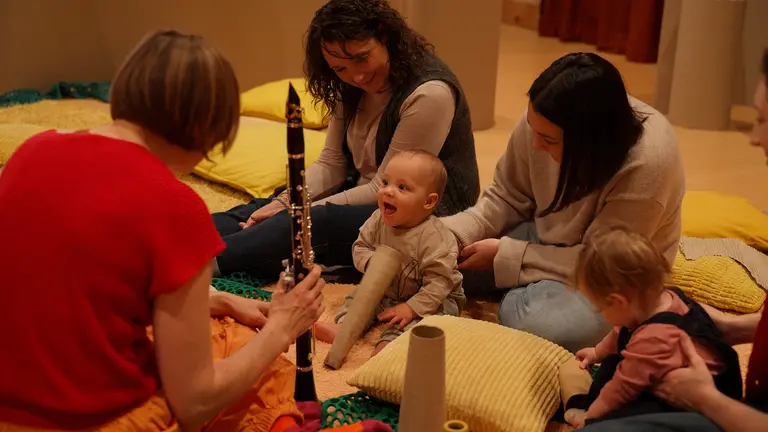Three adults and twi babies play and listen to the sound of instruments
