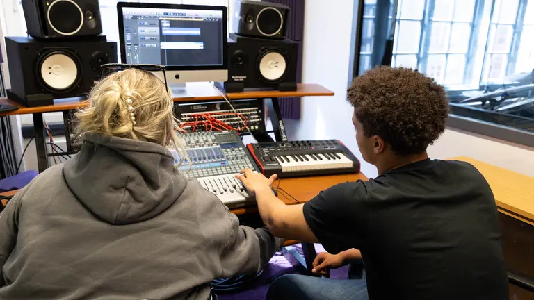 Two young people in front of a computer using a music software