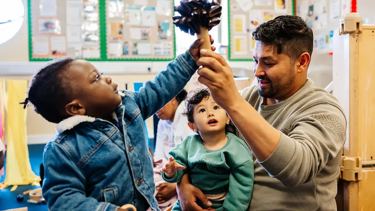 two young children at an early years project grabbing a toy from an adult