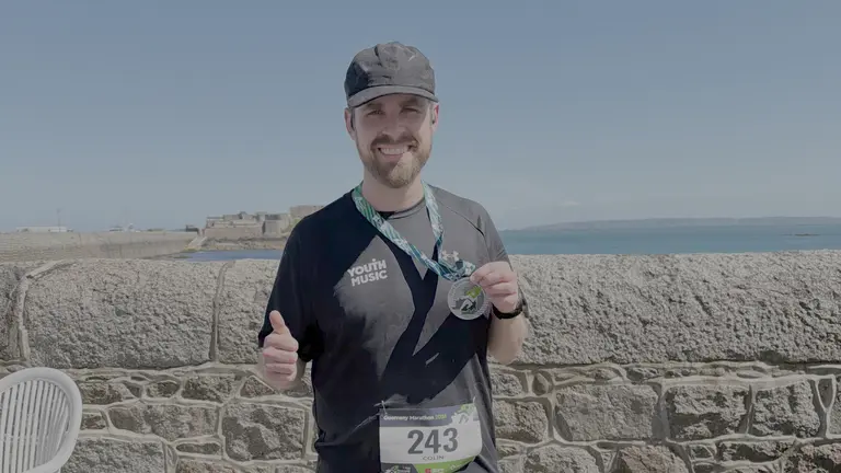 Man gives the thumbs up to camera after completing a marathon