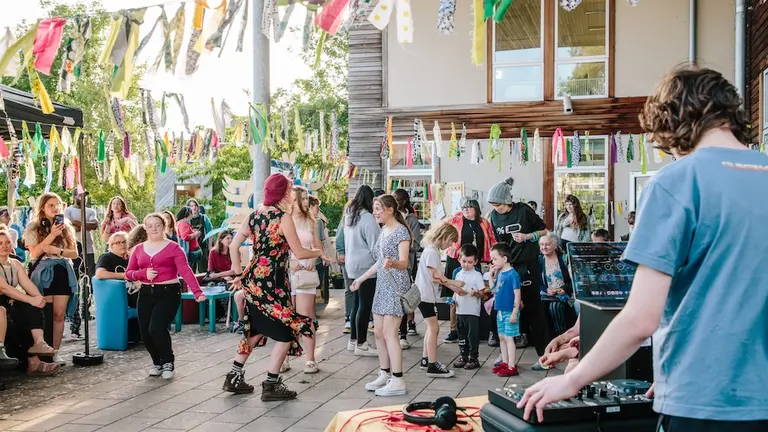 A outdoors party with a DJ and adults and children dancing 