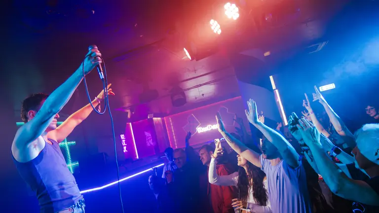 performer on stage with both hands in the air in front of the audience with their hands in the air