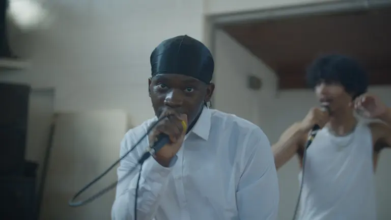 Young person singing/speaking into a mic looking at the camera