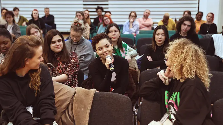 A person speaking into a microphone within an audience