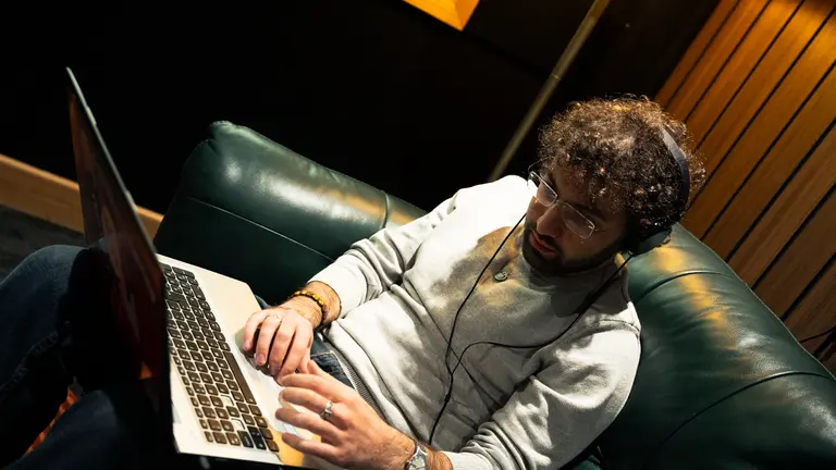 a man working at a laptop, with headphones on