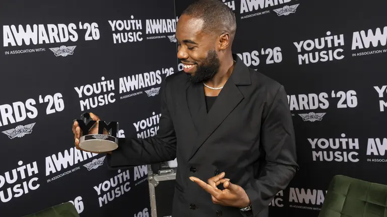 Righteous Reck smiling and pointing at his Youth Music Award