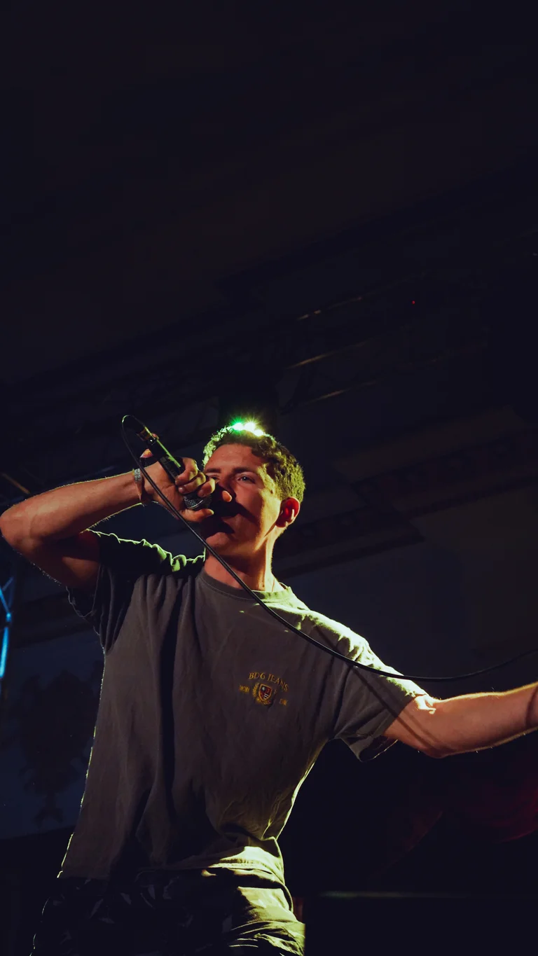 hulton holds a mic and performs on stage