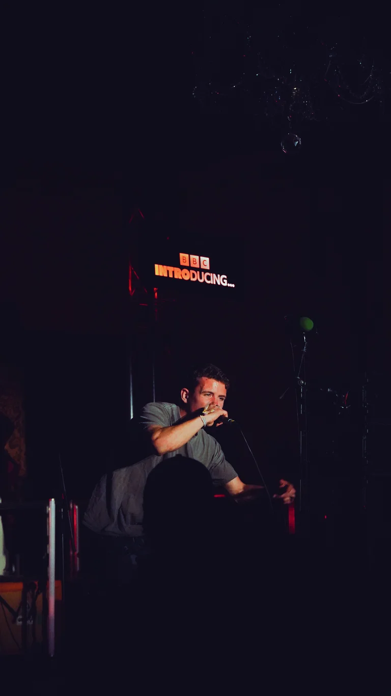hulton holds a mic and performs on stage