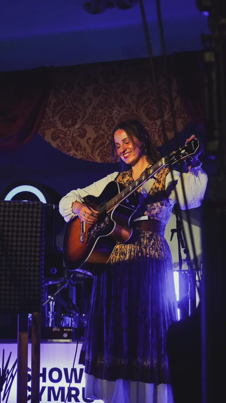 mari mathias holds her guitar on stage