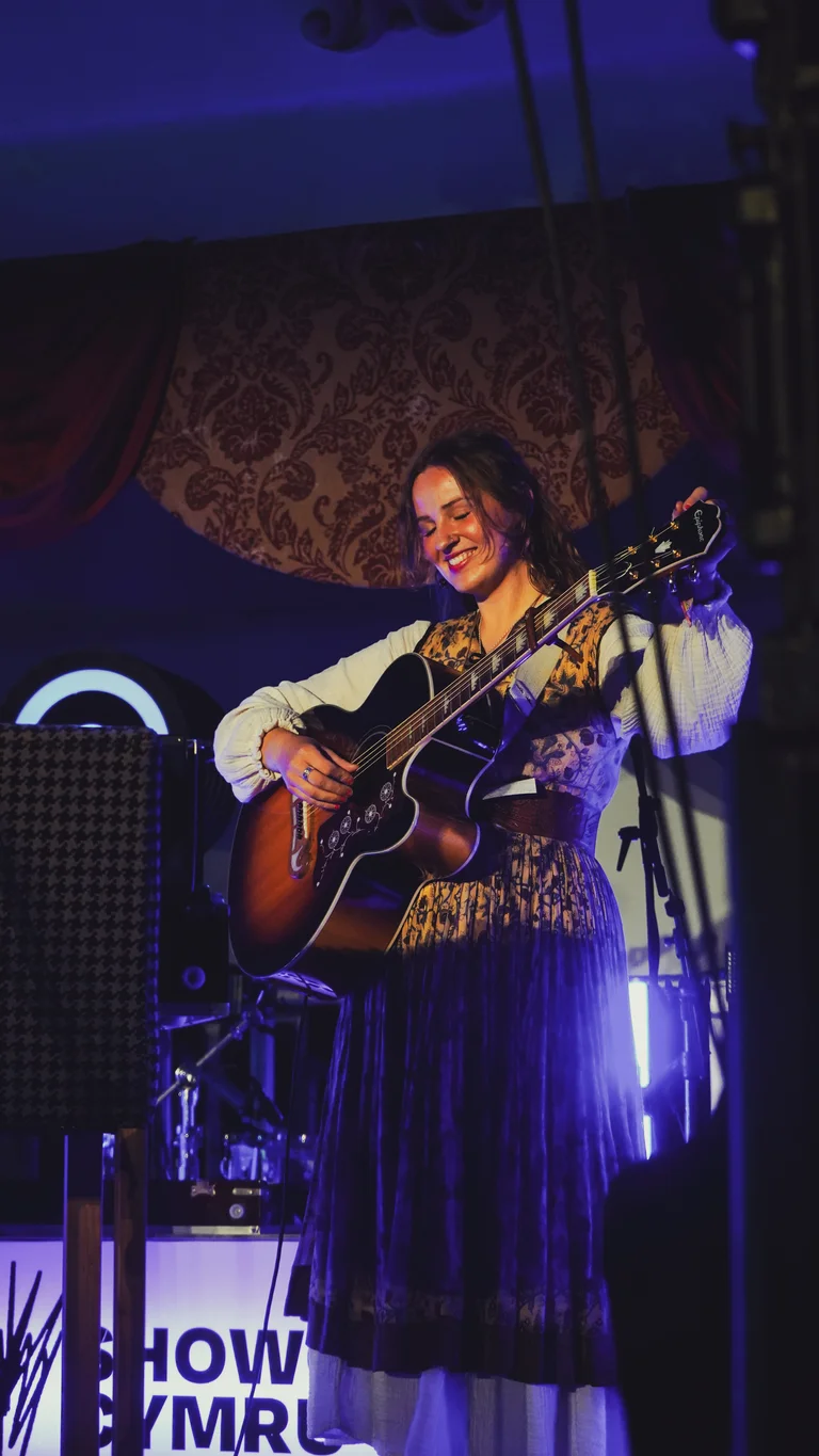 mari mathias holds her guitar on stage