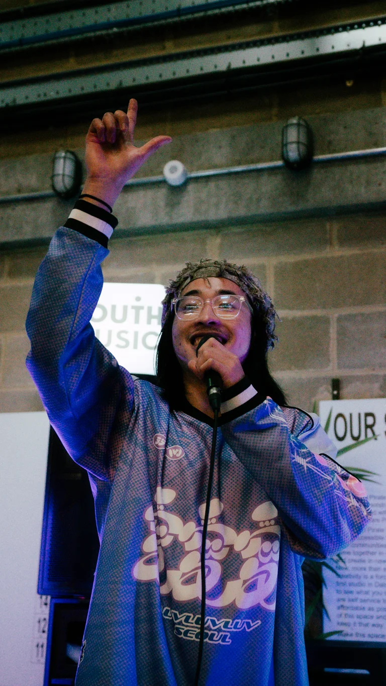a musician holds their arm up and speaks into a mic