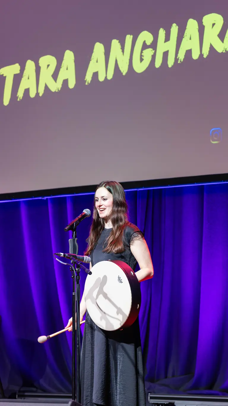 tara holds a drum on stage