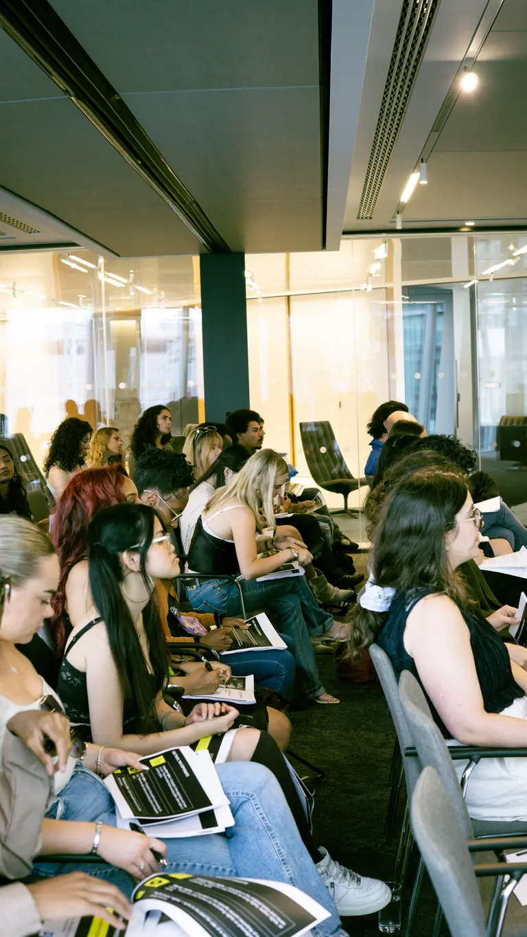 a busy room full of seated people use laptops