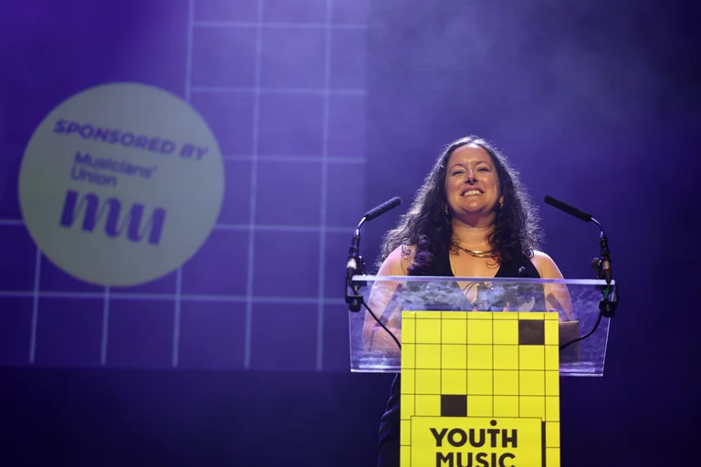 An image of an award winner smiling at the lecturn at the Youth Music Awards