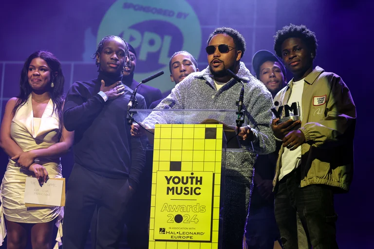 Benjamin Turner on stage at the YMAs, sunglasses on, accepting an award