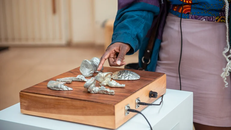 a hand reaches out to touch parts of an instrument called the sonic mind