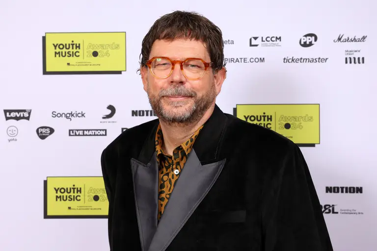 Matt Griffiths at the Youth Music Awards, wearing a black suit with grey lapels, a tiger print shirt, and red-rimmed glasses