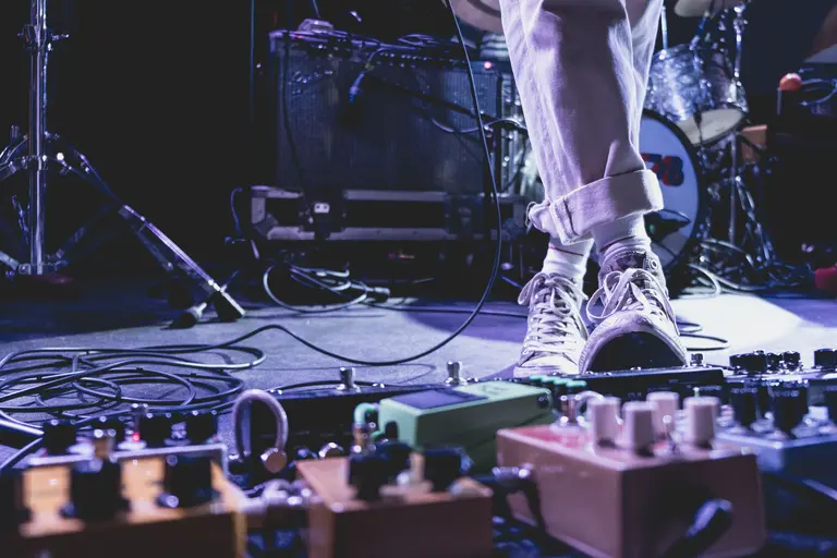 a person in a stage wearing white trousers and white all stars sneakers. 
