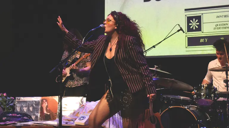 megan black performs on stage, singing into a mic