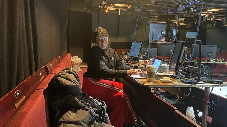 sarah sits at a sound tech desk in a theatre