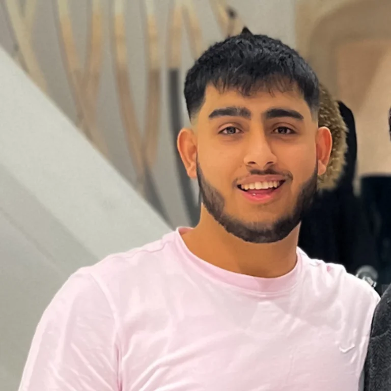 Usman Sheikh wearing a light pink shirt smiling at the camera