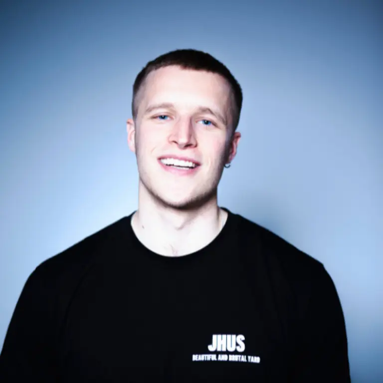 Max Wood headshot. He's smiling, with short hair, and a black top on, with a blue background
