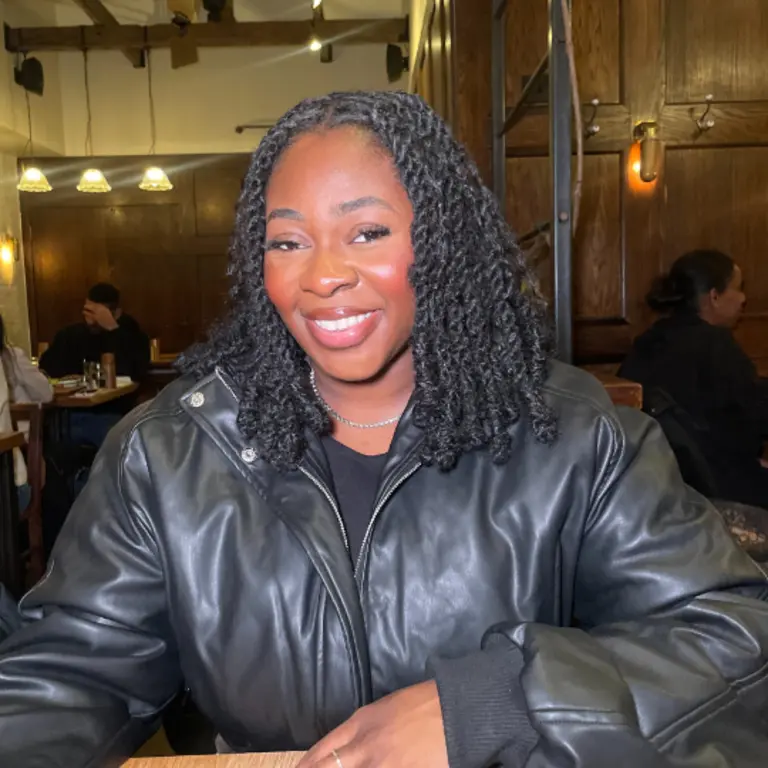 Cherise wearing a leather jacket at a table in a restaurant, smiling at the camera