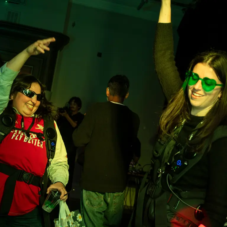 two girls dance smiling one with green love heart glasses and the other in an Arsenal top