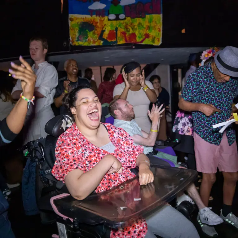 People enjoying a busy, inclusive live music event, with disabled and non‑disabled attendees dancing and engaging together. 